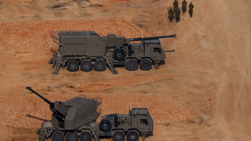 Israeli soldiers walk near artillery vehicles, near the Israel-Lebanon border, in northern Israel, April 15, 2026. REUTERS/Florion Goga