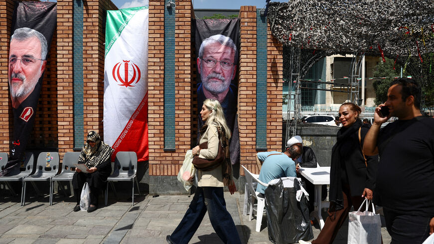 A woman walks past a banner with a picture of the late Iranian security chief Ali Larijani in Tehran Bazaar, April 21.  Majid Asgaripour/WANA
