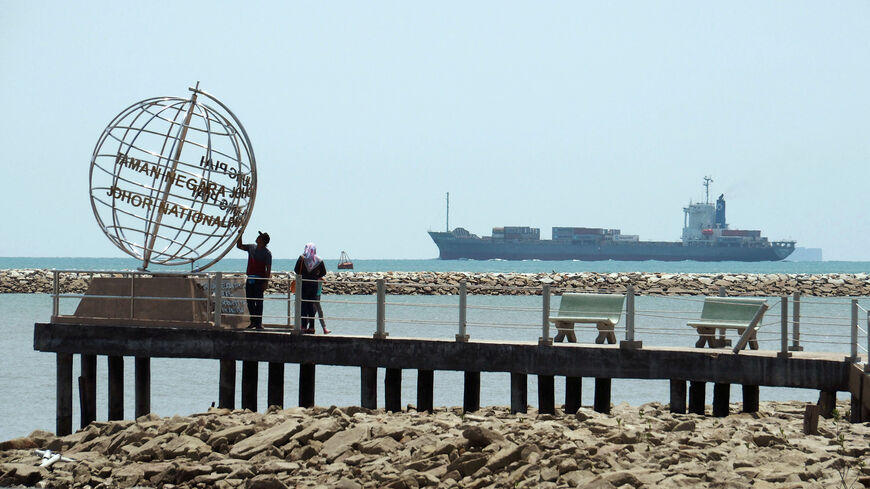 FILE PHOTO: A container ship enters the Singapore Strait for the Strait of Malacca, as tourists stand at mainland Asia's southern most point in Johor, Malaysia November 12, 2016. Picture taken November 12, 2016.  REUTERS/Henning Gloystein/File Photo