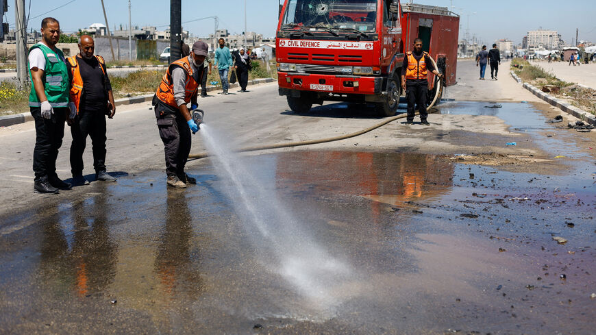 Members of civil defence personnel use a fire hose at the site of an Israeli airstrike on a car in the central Gaza Strip, April 23, 2026. REUTERS/Mahmoud Issa