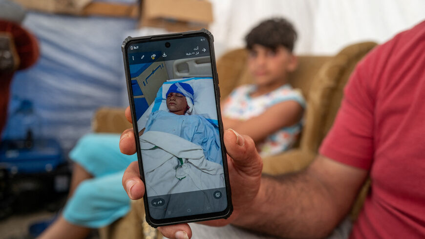 Rabih Khreisse, 44, a displaced Lebanese man from the southern village of Khiyam, near the border with Israel, shows a photograph of his son Ziad, 11, lying in a hospital after being wounded in an Israeli strike in 2024, as they sit at their shelter in a makeshift encampment, amid a temporary ceasefire between Lebanon and Israel, in Beirut, Lebanon April 27 2026. REUTERS/Zohra Bensemra