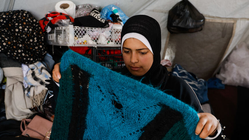 Palestinian bride-to-be Amani Abu Selmi holds damaged wool clothes inside a tent, after they were bitten by rodents, in Khan Younis in the southern Gaza Strip, April 26, 2026. REUTERS/Haseeb Alwazeer