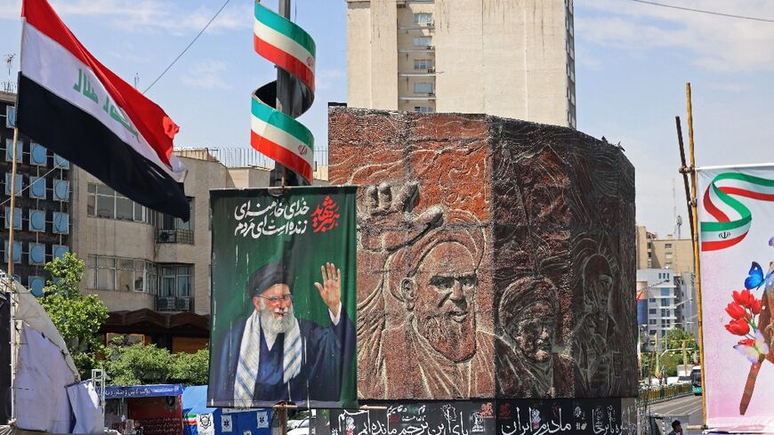 Commuters make their way past a picture of Iran's slain supreme leader Ayatollah Ali Khamenei (L) and a sculpture of late supreme leader Ayatollah Ruhollah Khomeini in Tehran