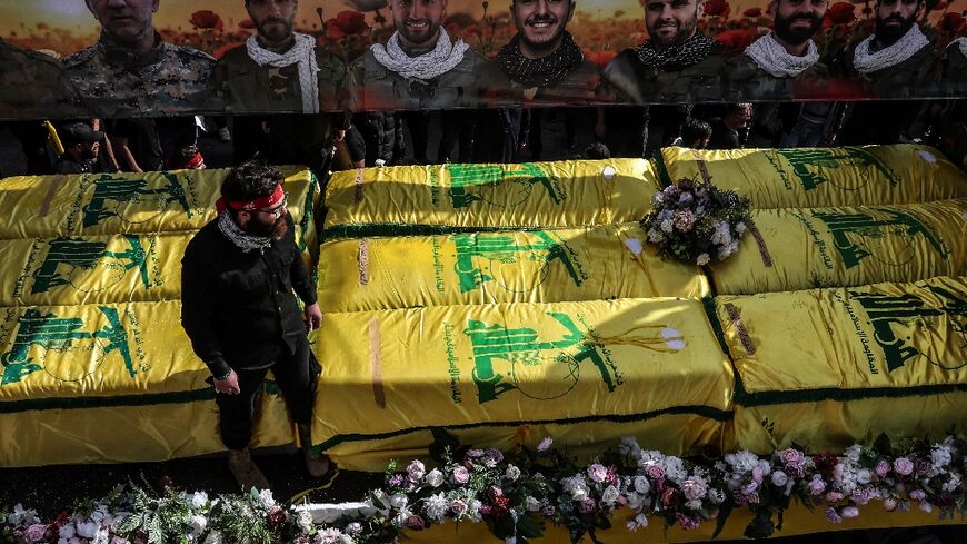 Coffins sit on a trailer beneath portraits of Hezbollah fighters killed in Lebanon by Israel before a 10-day ceasefire was agreed