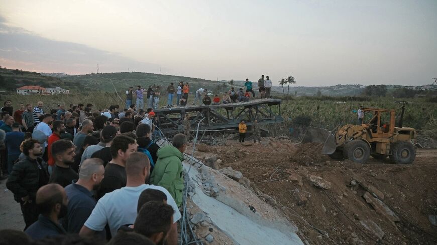 People watch as bulldozers work to reopen the Qasmiyeh bridge over the Litani River in south Lebanon