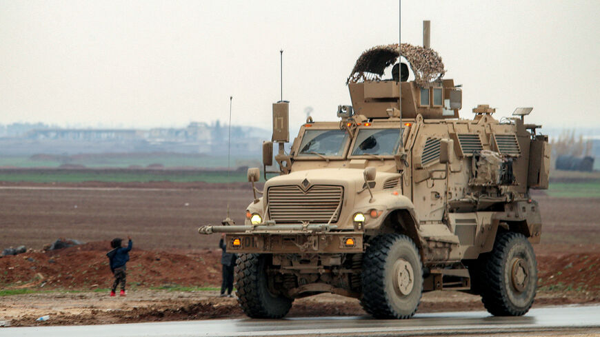 Boys along a road wave to an approaching US military mine-resistant ambush protected (MRAP) armored fighting vehicle moving in a convoy transporting Islamic State group detainees being transferred to Iraq from Syria, on the outskirts of Qahtaniyah in Syria's northeastern Hasakah province on Feb. 7, 2026.