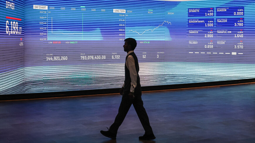 A man walks past a screen displaying stock indices at the Dubai Financial Market stock exchange in Dubai, March 4, 2026.