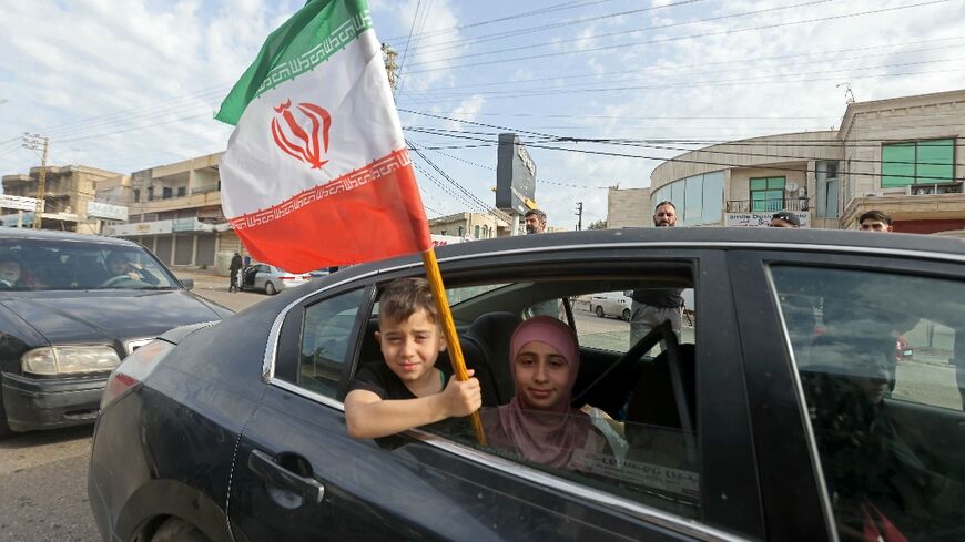 A boy holds an Iranian flag as he returns back to the southern Lebanese town of Marwanieh