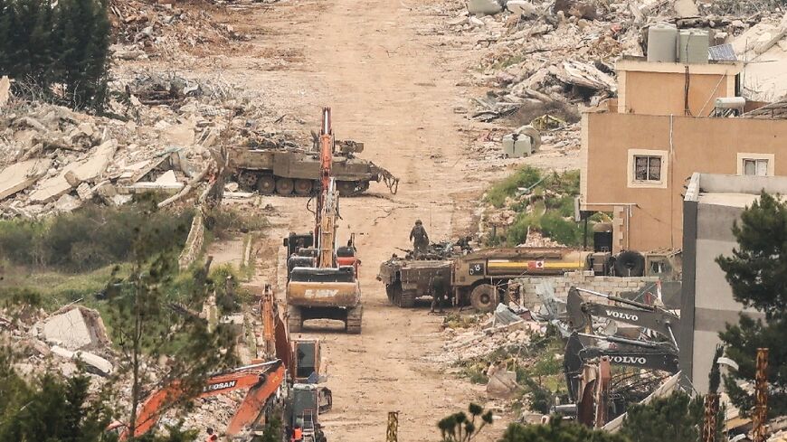 From the Israeli side of the border with Lebanon Israeli army armoured vehicles and excavators are visible among destroyed buildings
