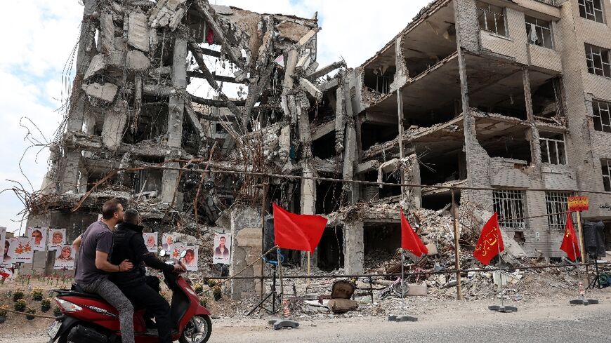 Iranians stop to look at portraits of victims reportedly killed in a US-Israeli airstrike on a residential building in Tehran