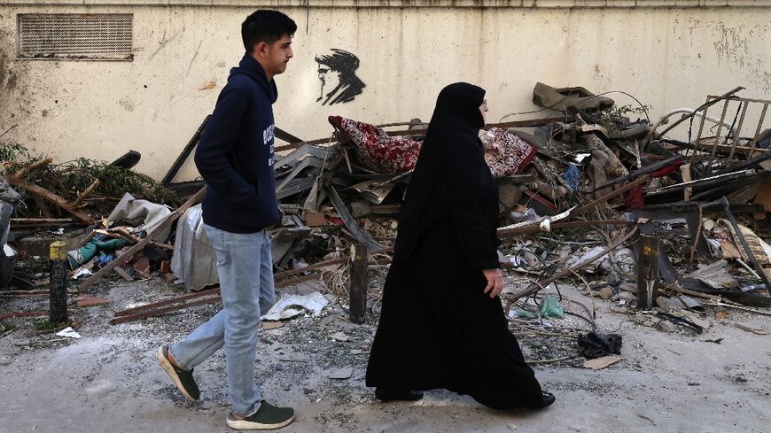 Residents walk past scattered debris at the site of an Israeli airstrike in the Lebanese capital Beirut