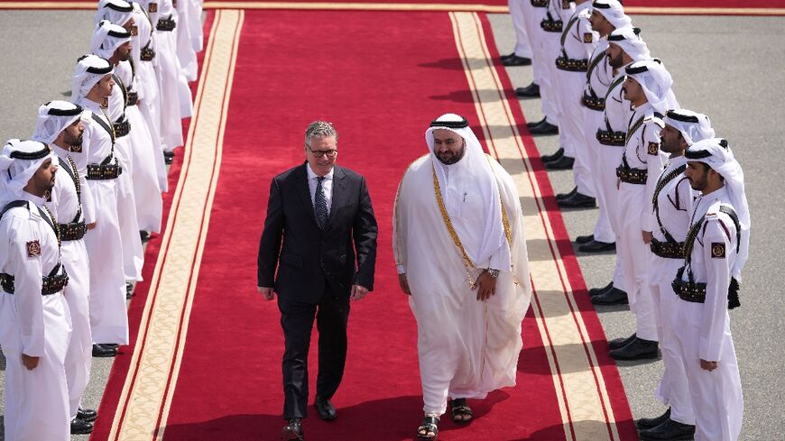 Qatari minister Mohammed al-Khulaifi bids farewell to Britain's Keir Starmer (L) at Doha airport