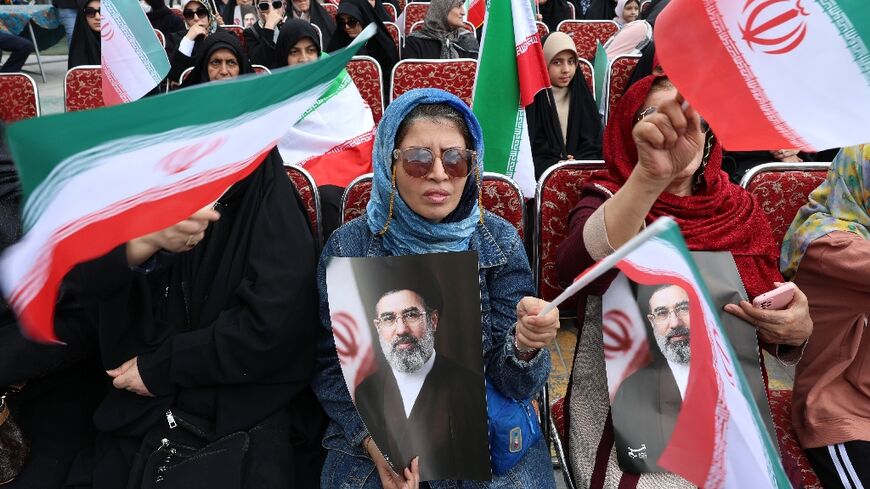 Iranian women hold portraits of Iran's supreme leader Mojtaba Khamenei while gathering in front of Tehran's Mellat park during "Sizdeh Bedar" (Nature Day), the 13th day after the Nowruz Persian New Year