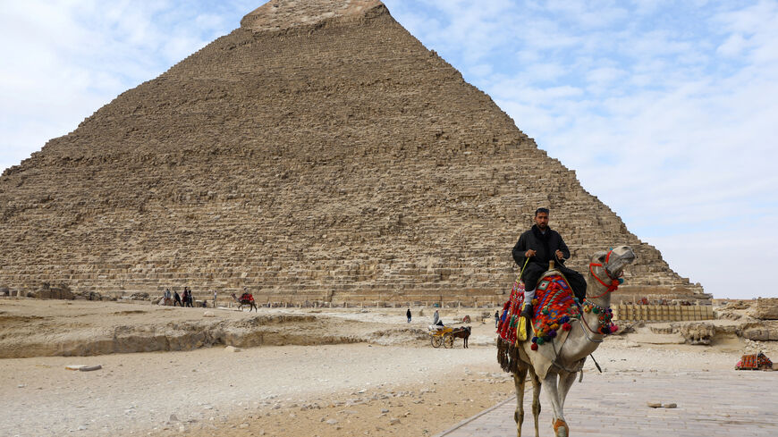 FILE PHOTO: A man waits for tourists to rent his camel in front of the Pyramid of Khufu, the largest of the Great Pyramids of Giza, on the outskirts of Cairo, Egypt January 18, 2020. REUTERS/Marius Bosch/File Photo