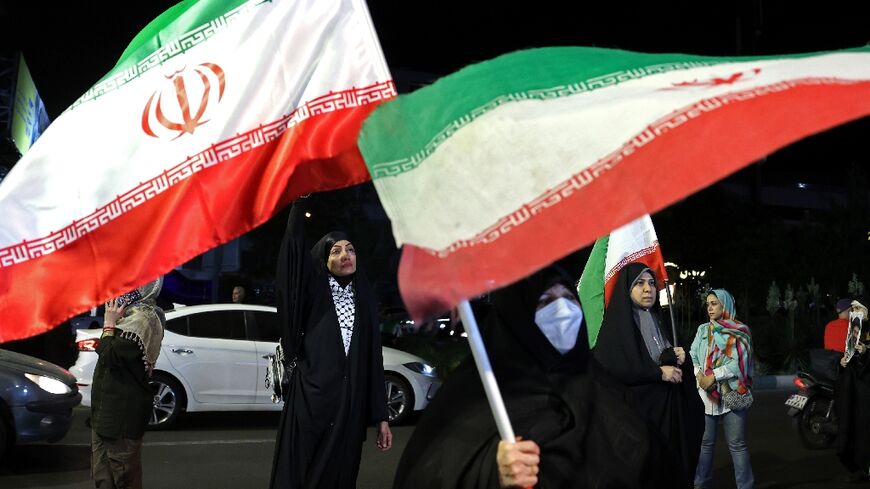 Women hold Iran's national flags during an anti-US and Israel protest in Tehran 