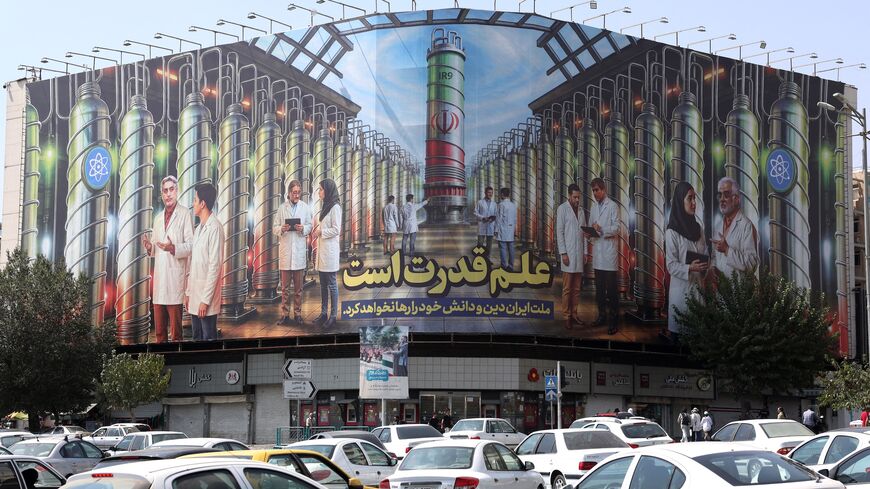 Iranians drive next to a billboard displaying pictures of nuclear scientists, centrifuges and a sentence reading in Farsi " Science is the power," at the Enqelab Square in Tehran, on Aug. 29, 2025. 