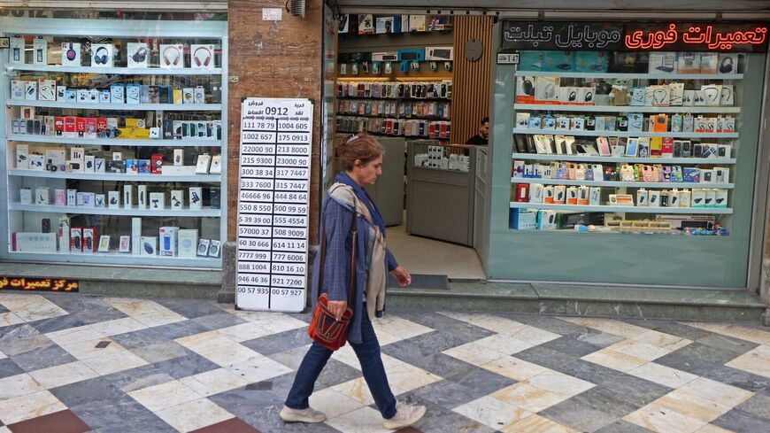 An Iranian woman walks past a mobile phone shop at the Valiasr Square in Tehran on April 19, 2026. — ATTA KENARE / AFP via Getty Images