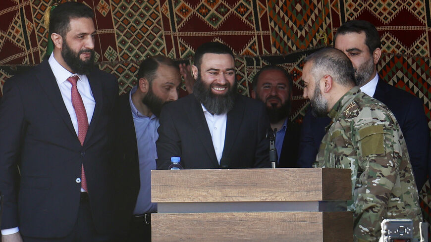 Syrian President Ahmed al-Sharaa (L) stands next to former Syrian rebel leader Issam Buwaydani (C), during a function in Douma on April 23, 2026. Buwaydani returned to Damascus on April 23 nearly a year after his detention for unknown reasons in the United Arab Emirates, a Syrian military official told AFP. (Photo by Bakr ALKASEM / AFP via Getty Images)