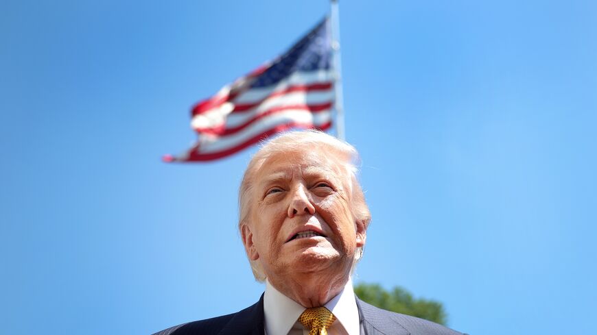 President Donald Trump speaks in front of the American flag to the press as he departs the White House on May 12, 2026, in Washington, DC. 
