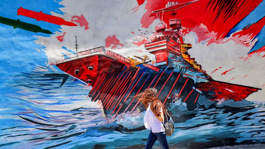 A woman walks past an anti-US and anti-Israel mural depicting missiles hitting an aircraft carrier in Tehran on May 26, 2026.