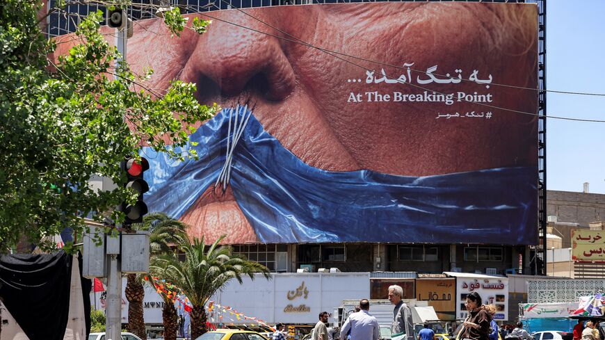 Motorists drive their vehicles and pedestrians cross the street past a political billboard featuring President Donald Trump and the Strait of Hormuz along Valiasr Square in Tehran on May 26, 2026.