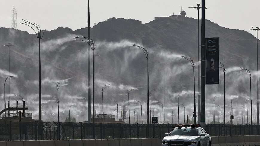 A police car drives past water-mist fans in Mecca ahead of the hajj pilgrimage when temperatures could reach 47 degrees Celsius