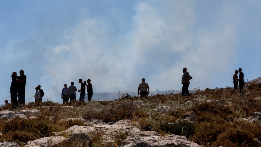 Palestinians observe smoke rising from a fire started by crowd control grenades thrown by Israeli troops, during a protest against a settlement near Hebron in the Israeli-occupied West Bank, June 9, 2026. REUTERS/Mussa Qawasma