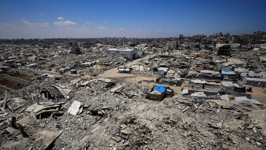 Palestinians make their way past the rubble of residential buildings destroyed during the Israeli offensive as displaced people shelter in tents, in Gaza City, June 15, 2026. REUTERS/Dawoud Abu Alkas