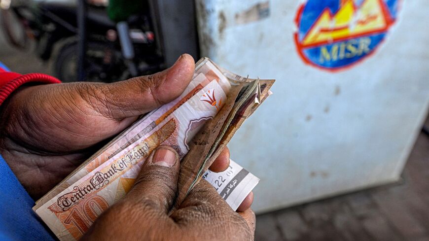 A worker counts banknotes after filling up the tank of a vehicle at a petrol station in Giza on March 10, 2026.
