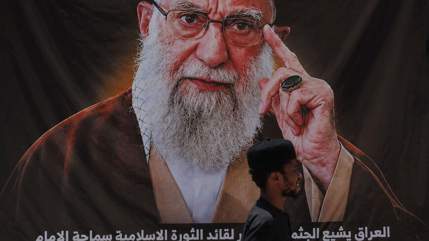 A man walks past a banner bearing a portrait of Iran's late Supreme Leader Ayatollah Ali Khamenei ahead of funeral processions in Najaf and Karbala, in Najaf, Iraq, July 7, 2026. REUTERS/Thaier Al-Sudani