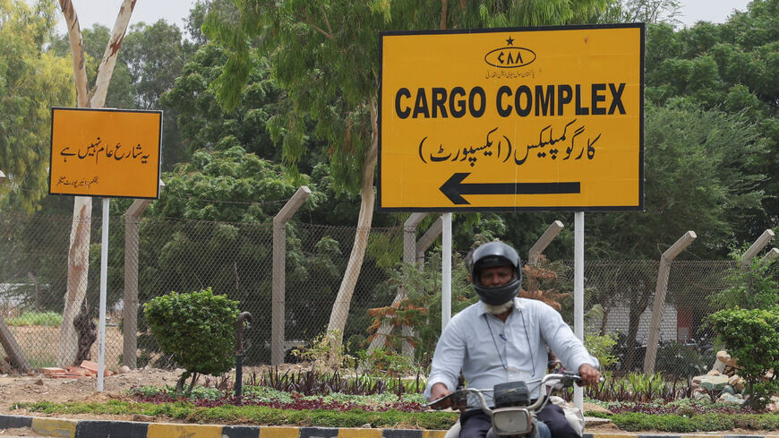 Men on a motorbike ride past a sign for the Cargo Complex at Jinnah International Airport, following reports of a missing cargo plane, in Karachi, Pakistan, July 8, 2026. REUTERS/Akhtar Soomro