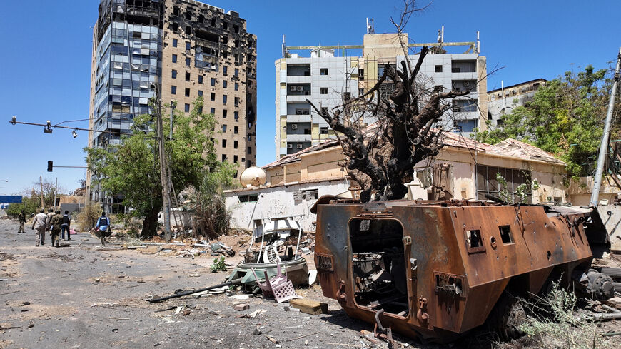 Members of army walks near a destroyed military vehicle and bombed buildings, as Sudan's army retakes ground and some displaced residents return to ravaged capital in the state of Khartoum Sudan March 26, 2025. REUTERS/El Tayeb Siddig