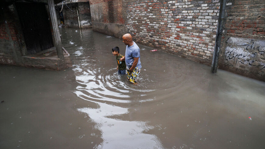 A man and a boy wade through a flooded street amid rain in Gujranwala, Pakistan, July 23, 2026. REUTERS/Syed Aftab Rizvi