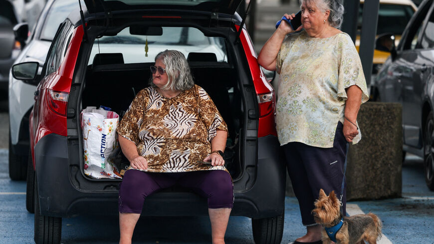 A woman carries a dog at the Bordeaux-Lac Exhibition Centre, which has been turned into a shelter for people displaced by a wildfire burning nearby amid worsening drought conditions following a heatwave and water shortages across much of France, in Bordeaux, Gironde, France, July 26, 2026. REUTERS/Florion Goga