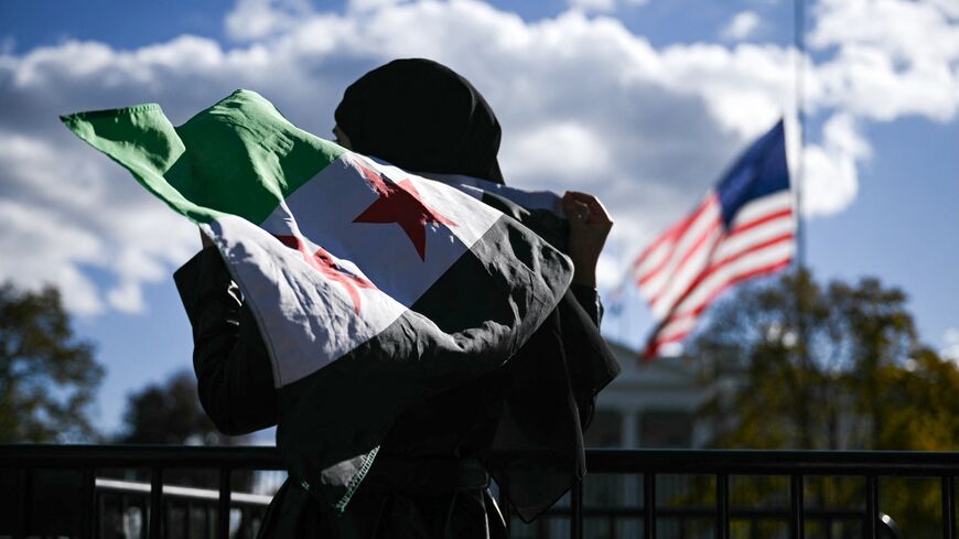 A man holds a Syrian flag across the street from the White House after Syrian President Ahmed al-Sharaa met with President Donald Trump at White House in Washington, on Nov. 10, 2025. 