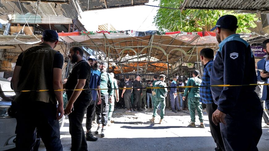 Syrian security forces and bystanders gather at the site of an explosion at a cafe in Damascus on Thursday