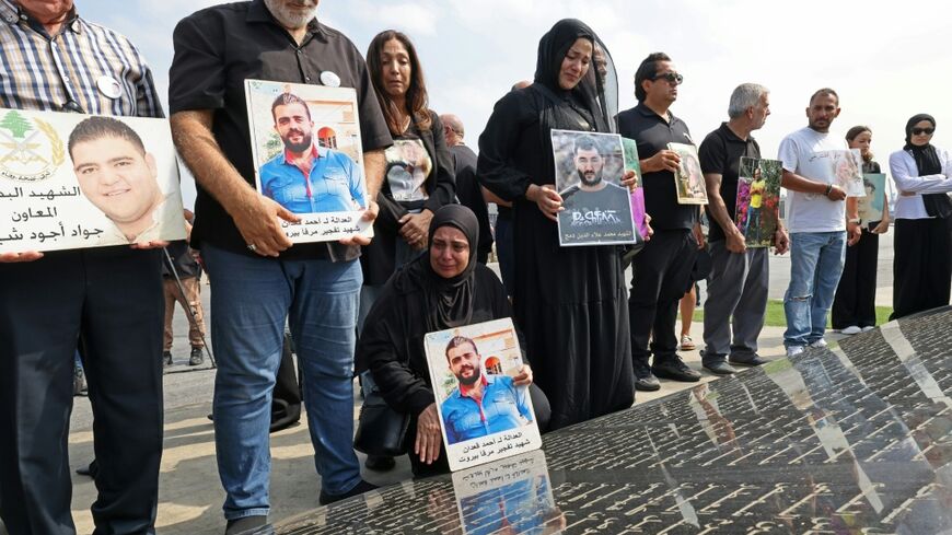 Family members carry the portraits of the victims of 2020 Beirut port blast as they gather around the marble memorial engraved with the names of the victims near the blast's ground zero