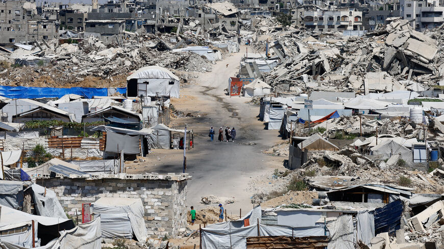 People walk at a site destroyed during the Israeli offensive, in Beit Lahiya, in the northern Gaza Strip, August 18, 2026. REUTERS/Mahmoud Issa