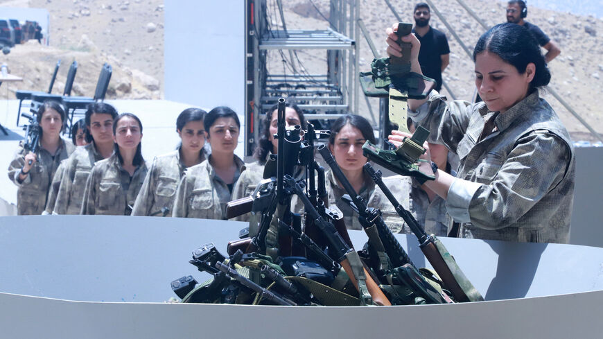 Fighters with the Kurdistan Workers' Party (PKK) line up to put their weapons into a pit during a ceremony in Sulaimaniyah, in Iraq's autonomous Kurdistan region, on July 11, 2025. 