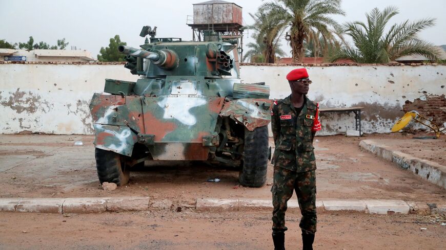Sudanese army soldier stands in front of a tank