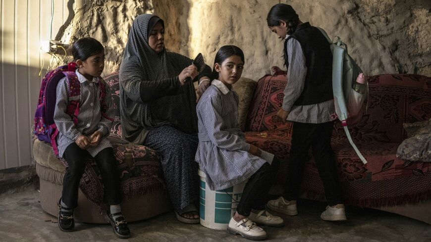 Arwa Emar brushes her daughter's hair as they prepare for school, inside a cave that the family has turned into their home
