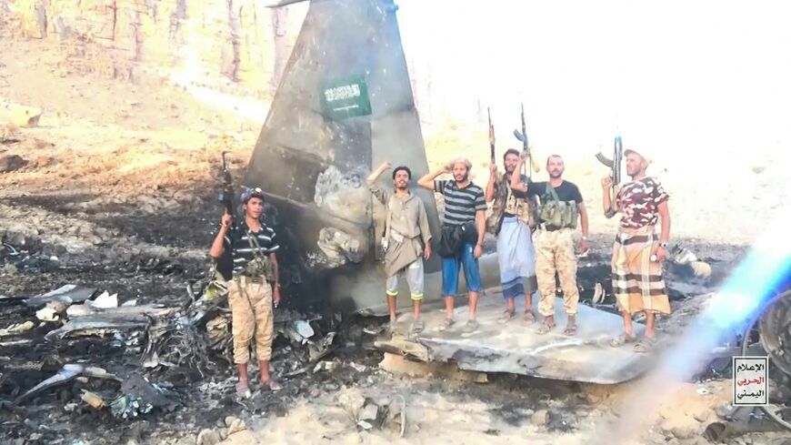 This handout picture released by Ansar Allah Media Centre shows Houthi fighters posing in the midst of what the Iran-backed group said is the wreckage of a Saudi F-15 fighter jet that was shot down in the central province of Marib