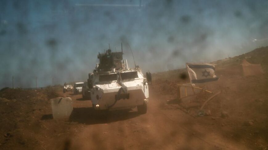 A UNIFIL convoy passes through a gate bearing Israeli flag, operated by an Israeli soldier, in Naqoura