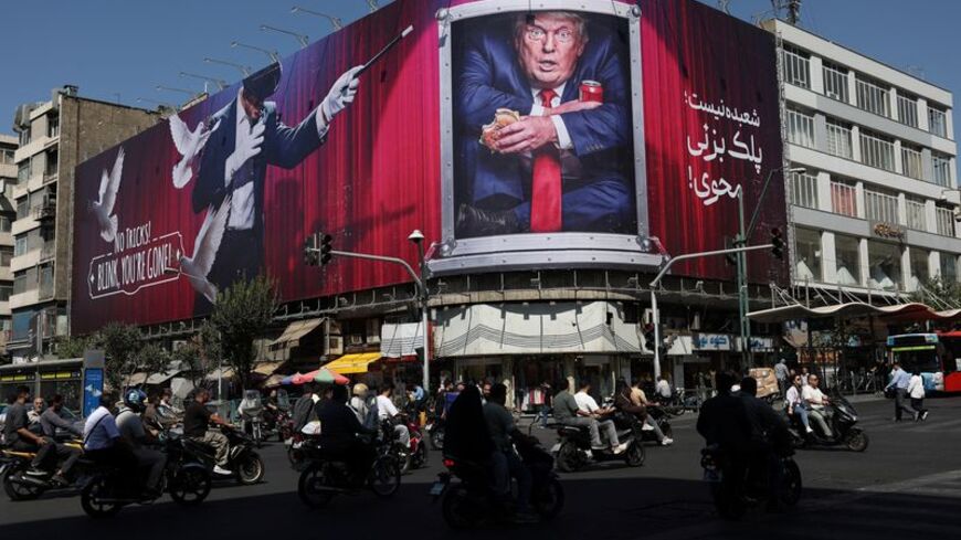 People drive near a billboard depicting U.S. President Donald Trump on a building in Tehran
