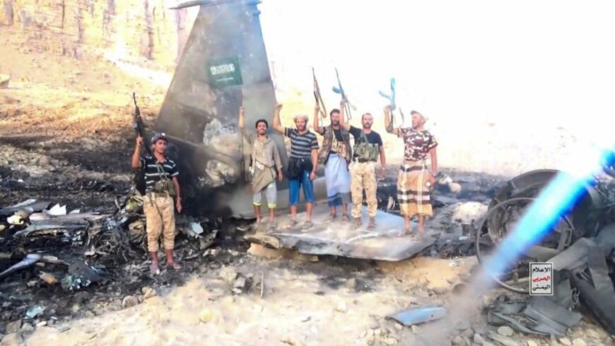 Houthi fighters stand in front of what they say is a downed Saudi jet, at a location given as Yemen