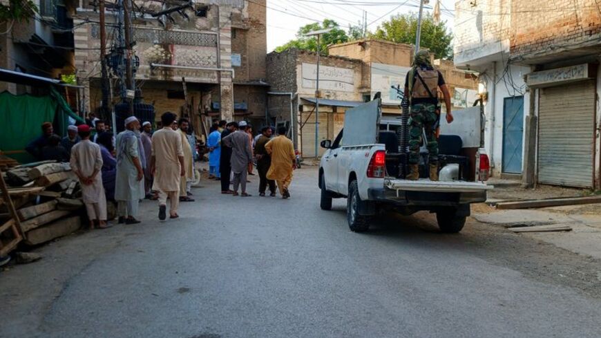 Residents and a police vehicle on a street following a suicide attack at a police facility in Kohat