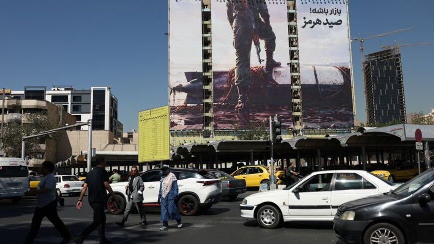 People walk past a billboard with a picture of an unmanned U.S. submersible, in Tehran