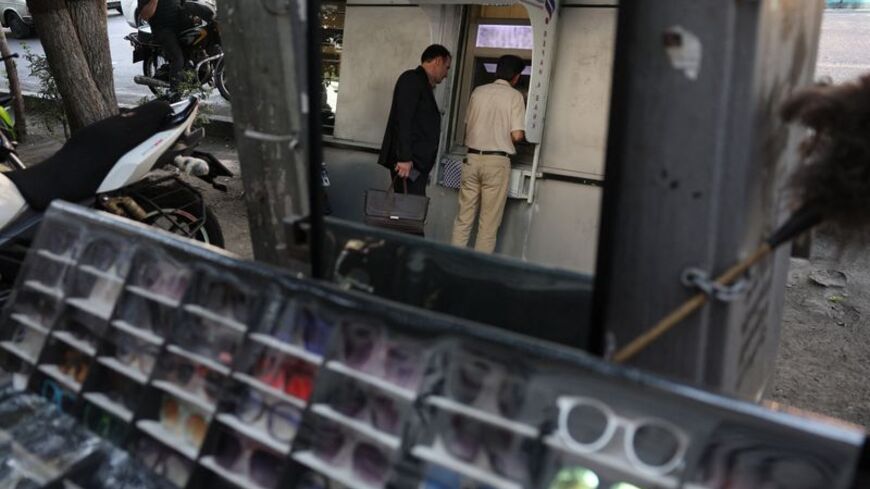 People use an ATM in front of a bank in Tehran