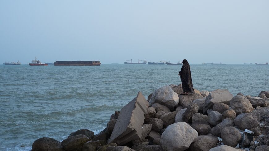 A women stands overlooking the water as ships are seen anchored in the Strait of Hormuz on Aug. 10, 2026, off the coast of Bandar Abbas, Iran.