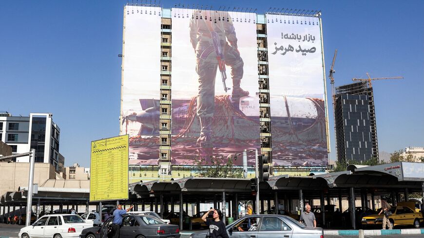 A woman crosses a street near a giant billboard erected on the facade of a building depicting a member of Iran's Islamic Revolutionary Guards Corps placing his foot on a US sea drone, reportedly seized by Iran in the Strait of Hormuz, in Vanak Square in Tehran, on Sept. 24, 2026.